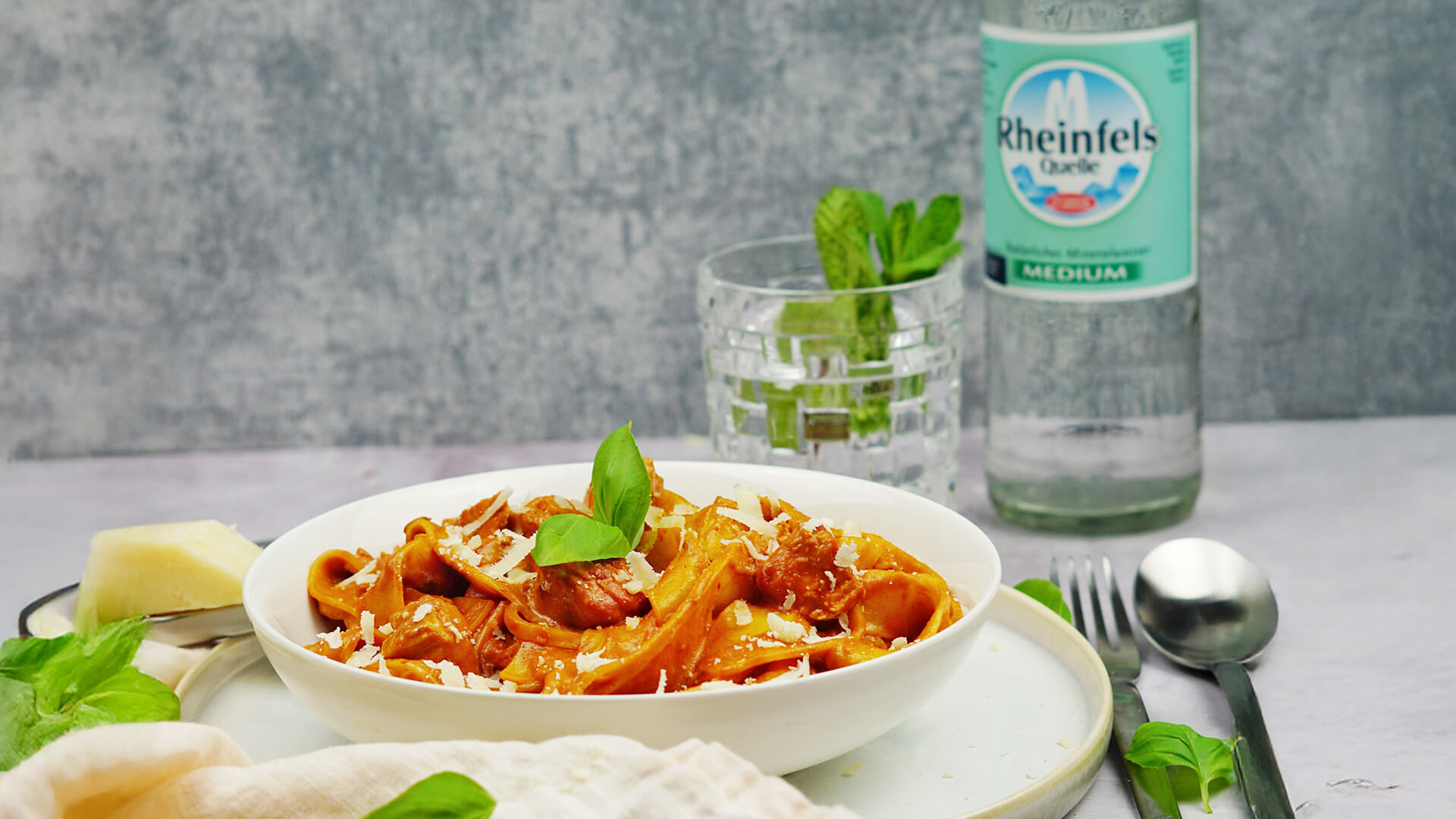 Ein Teller mit Pasta und eine Flasche Rheinfels Quelle Medium