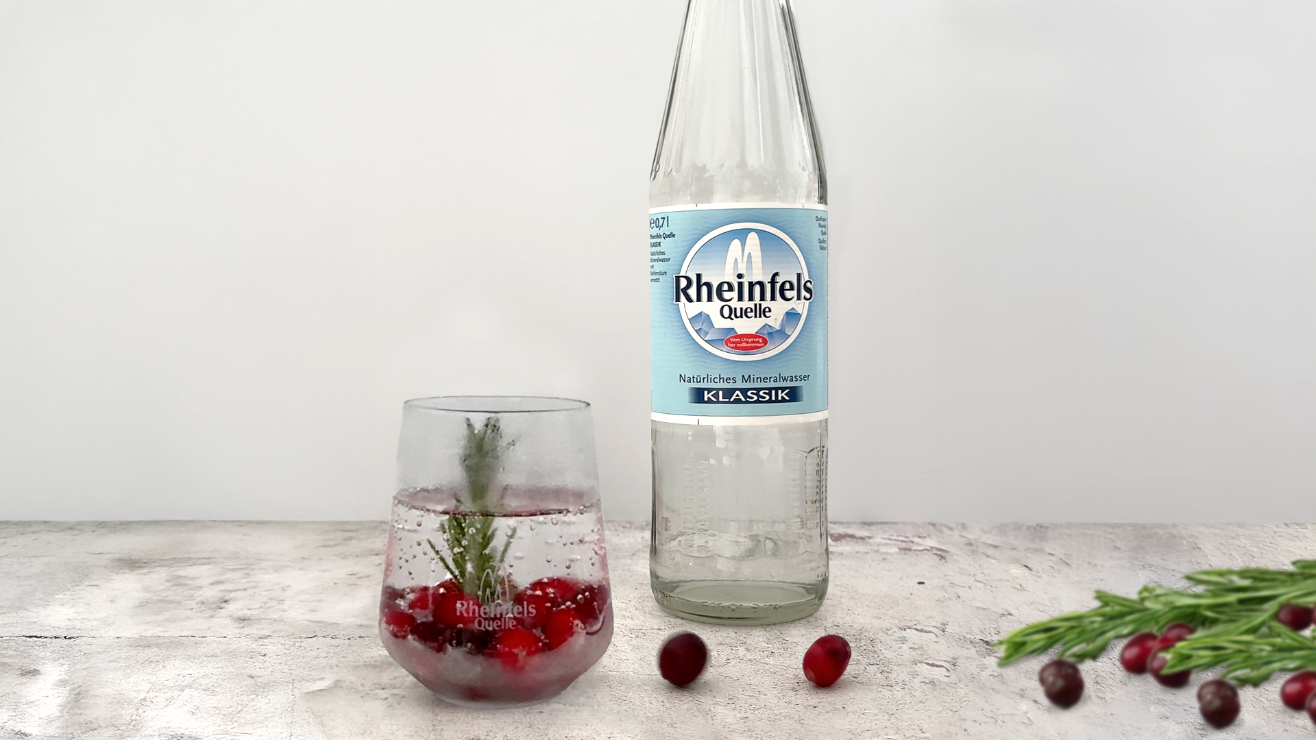 Der fertige Winter-Mocktail steht auf einem Tisch, daneben eine Flasche Rheinfels Quelle Klassik 0,7 L Glas Mehrweg.