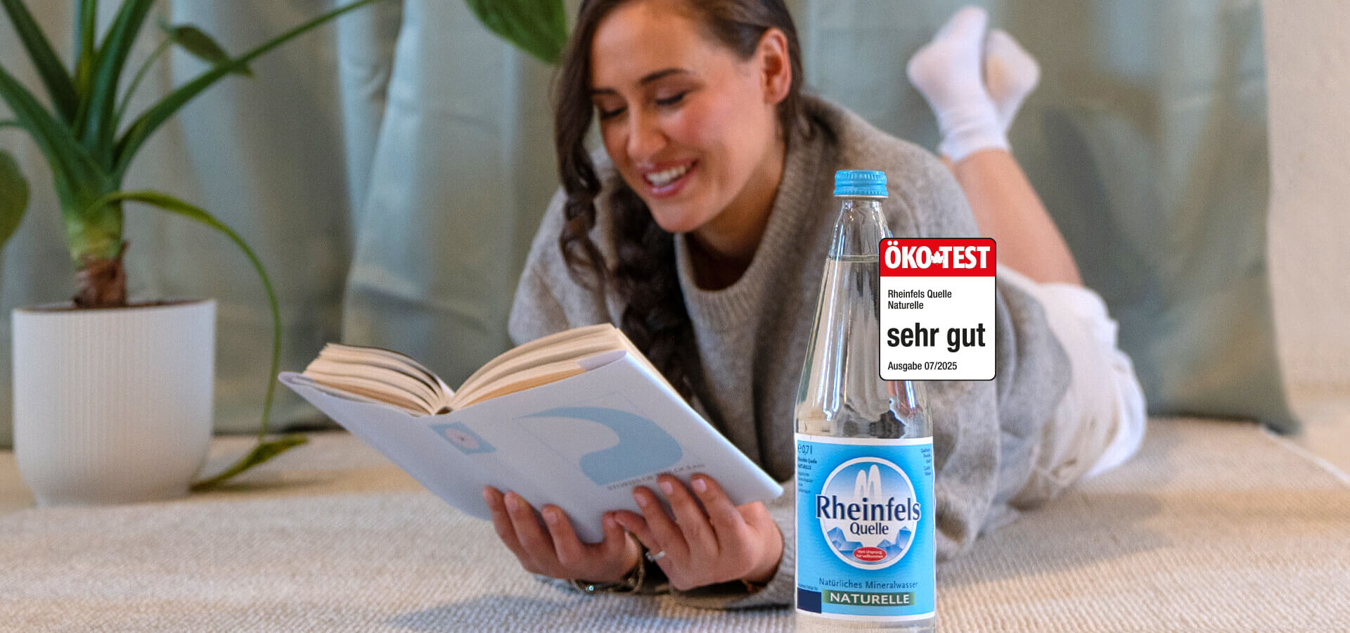 Frau hält Rheinfels Klassik Flasche in der Hand. Daneben ein Ökotest Siegel mit der Note sehr gut