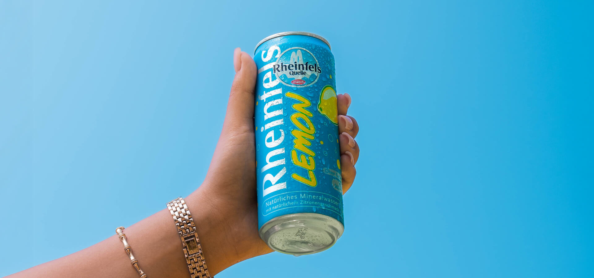 Eine gut gekühlte Dose Lemon, in der Hand vor strahlend blauen Himmel