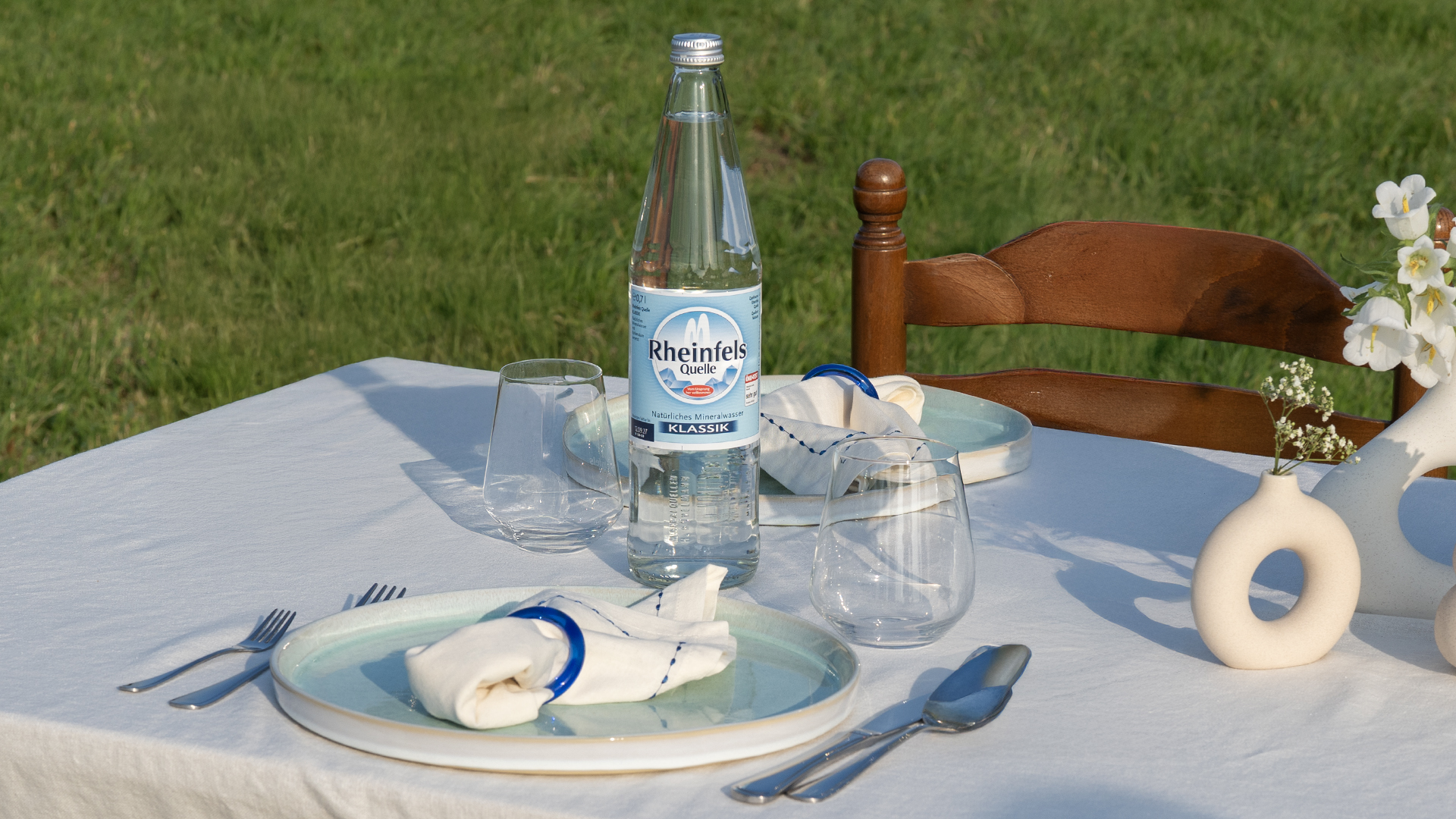 Rheinfels Quelle Klassik in der Glasflasche steht auf einem gedeckten Tisch.